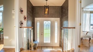 Un pasillo con puerta de cristal, suelo de madera y un banco.