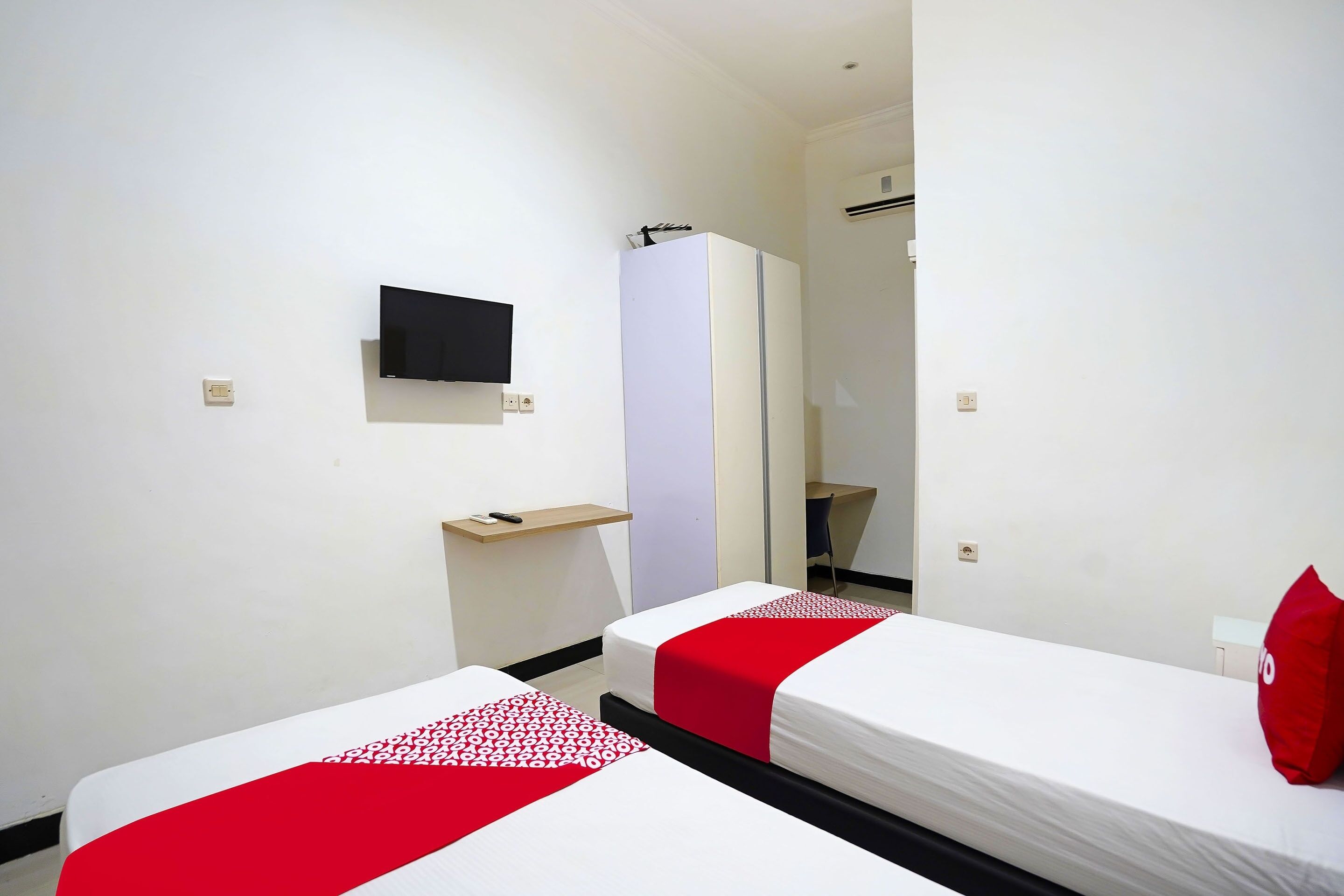 A hotel room with two beds, a TV, a mirror, and a small desk.
