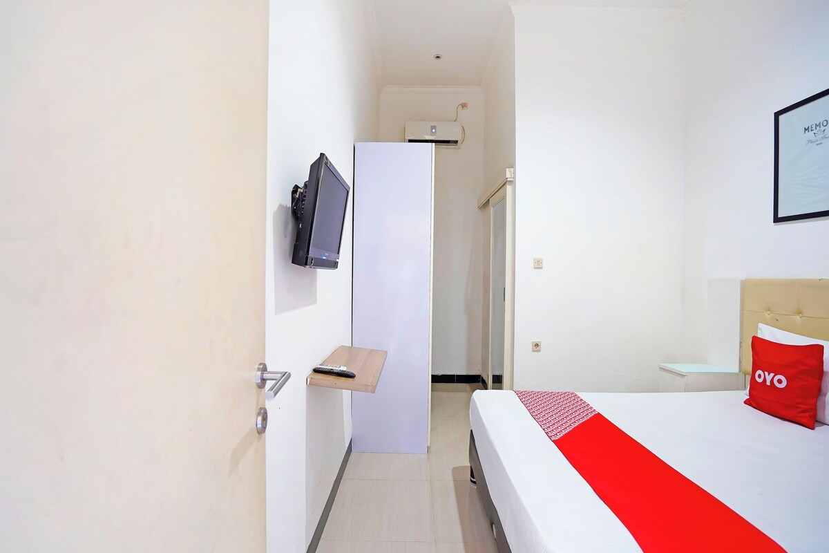 A hotel room with a bed, a TV mounted on the wall, a door, and a small table.