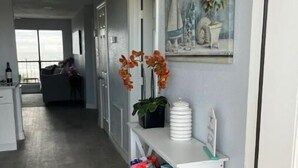 A hallway with a white console table, wicker baskets, and a painting of a sailboat.