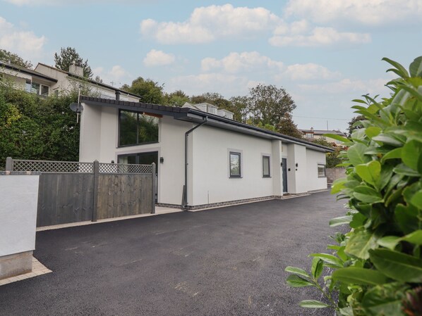 A modern two-story building with a white exterior, a wooden fence, and a paved driveway. - Bryn Cae (Llandudno)
