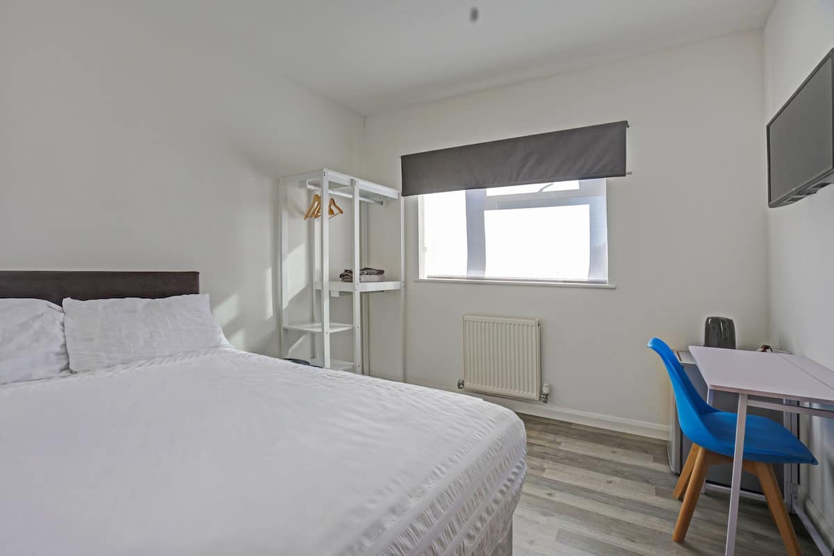 Ein Schlafzimmer mit Bett, Schreibtisch, Stuhl, Kleiderschrank und Fenster.