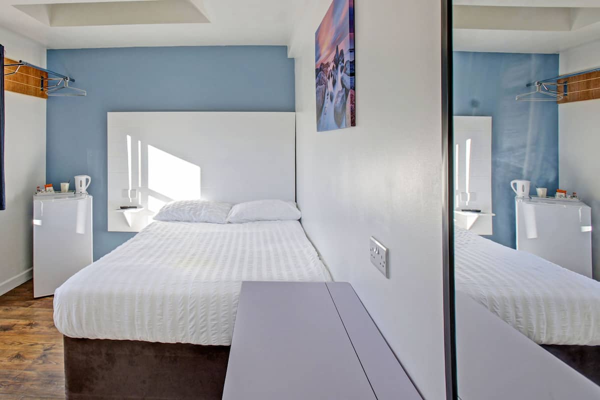 Ein modernes Schlafzimmer mit einem großen Bett, Nachttischen, einem Spiegel und einem Fenster.