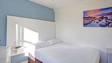 Un dormitorio con una cama, una mesita de noche y un cuadro en la pared.