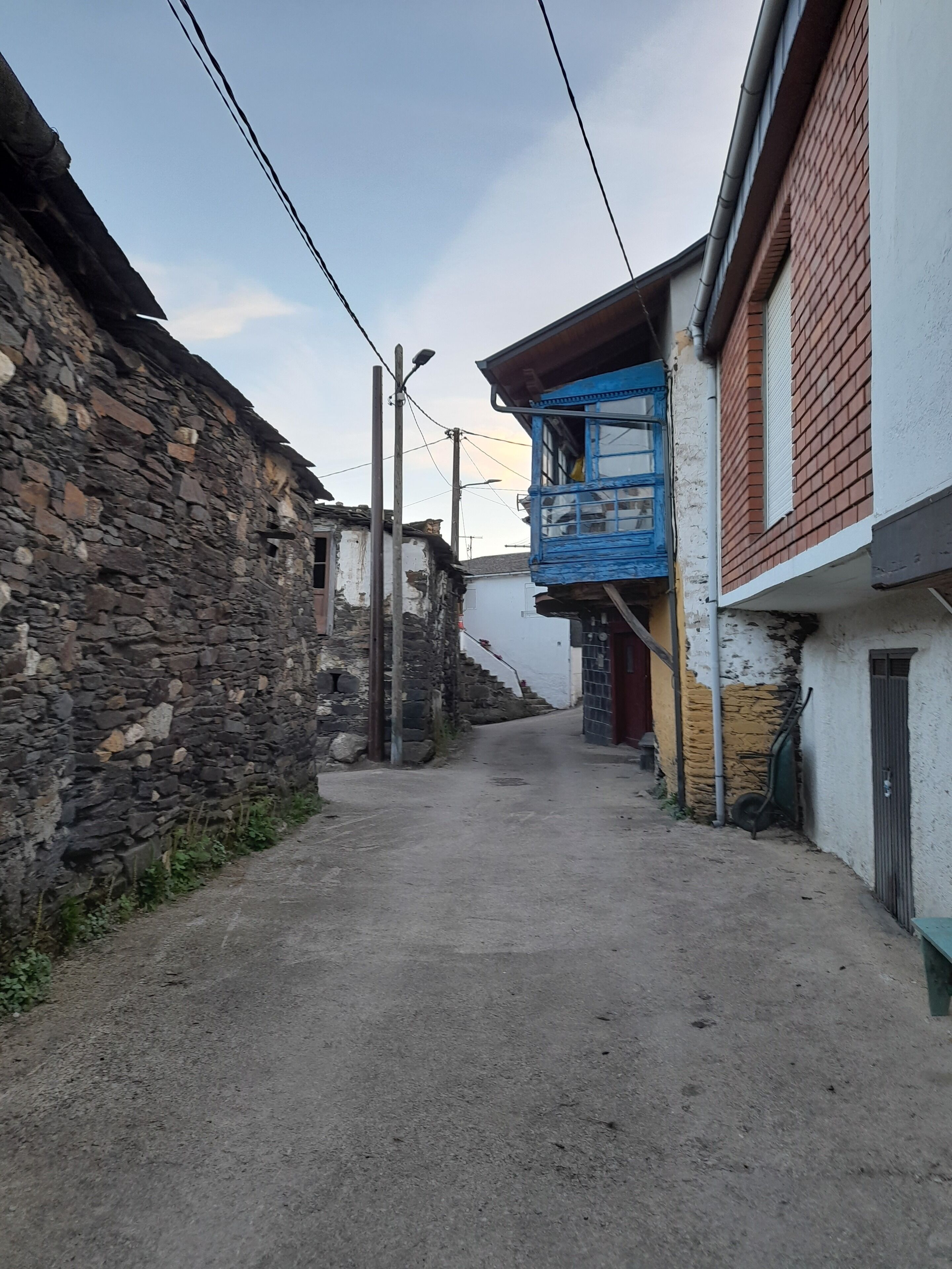 Un vicolo stretto con pareti in pietra su un lato e edifici in mattoni e intonaco dall'altro.