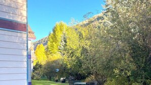 A residential property with a well-maintained lawn, a patio table and chairs, and a house with siding. - Bachman Village #9 - backyard and steps to skiing! (Telluride)