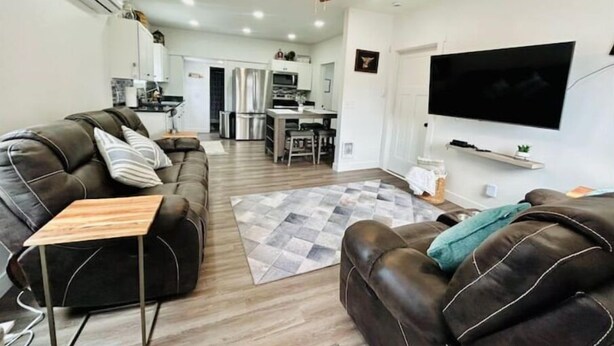 A modern living room with a leather sofa, a wooden coffee table, and a ceiling fan. - Modern Central Blackfoot Living (Blackfoot)