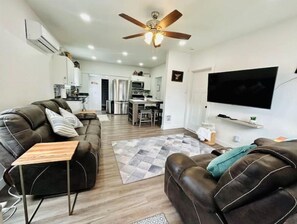 Un salon moderne avec un canapé en cuir, une table basse en bois et un ventilateur de plafond.