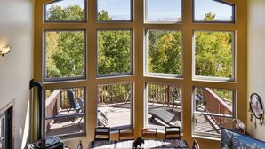 A room with multiple windows offering views of a deck and trees. - Native Retreat Cabin (Summit County)
