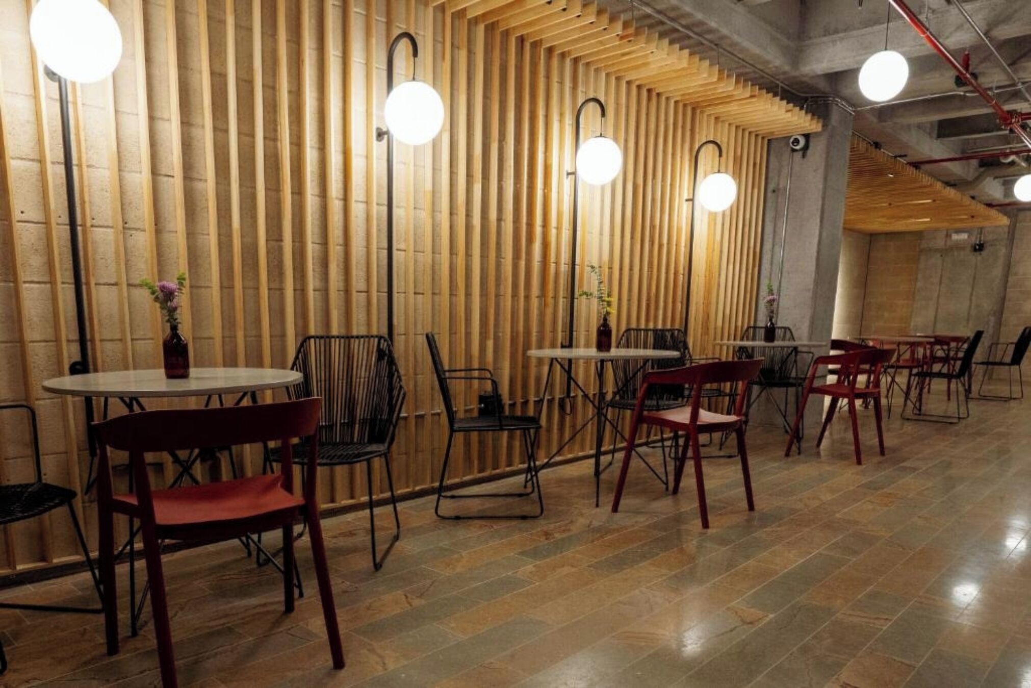 A restaurant interior with wooden slats on the walls, round tables, and chairs.