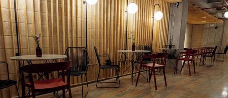 A restaurant interior with wooden slats on the walls, round tables, and chairs.