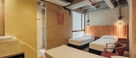 A hotel room with two beds, a bathroom with a sink, and a window with a view.