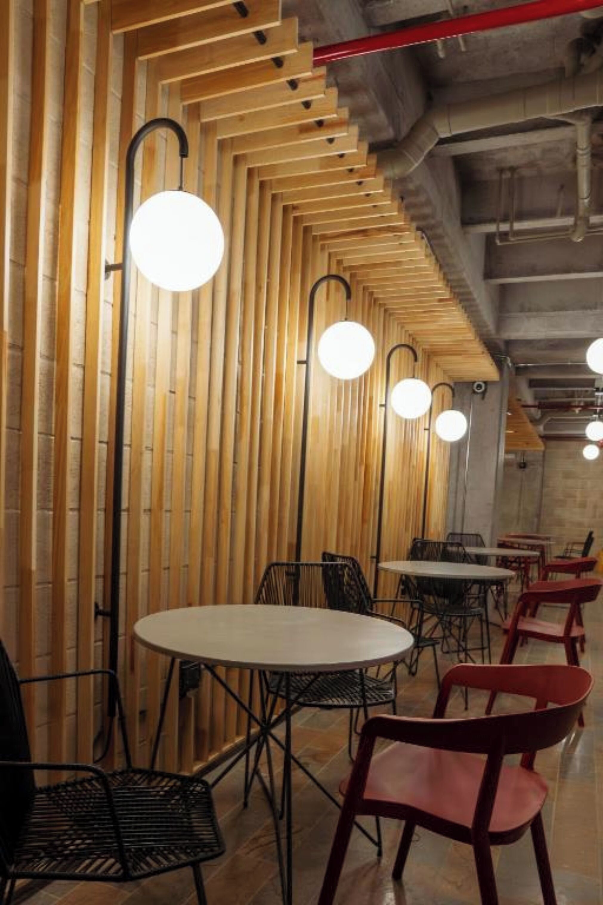 A restaurant interior with wooden slat walls, round tables, and chairs.