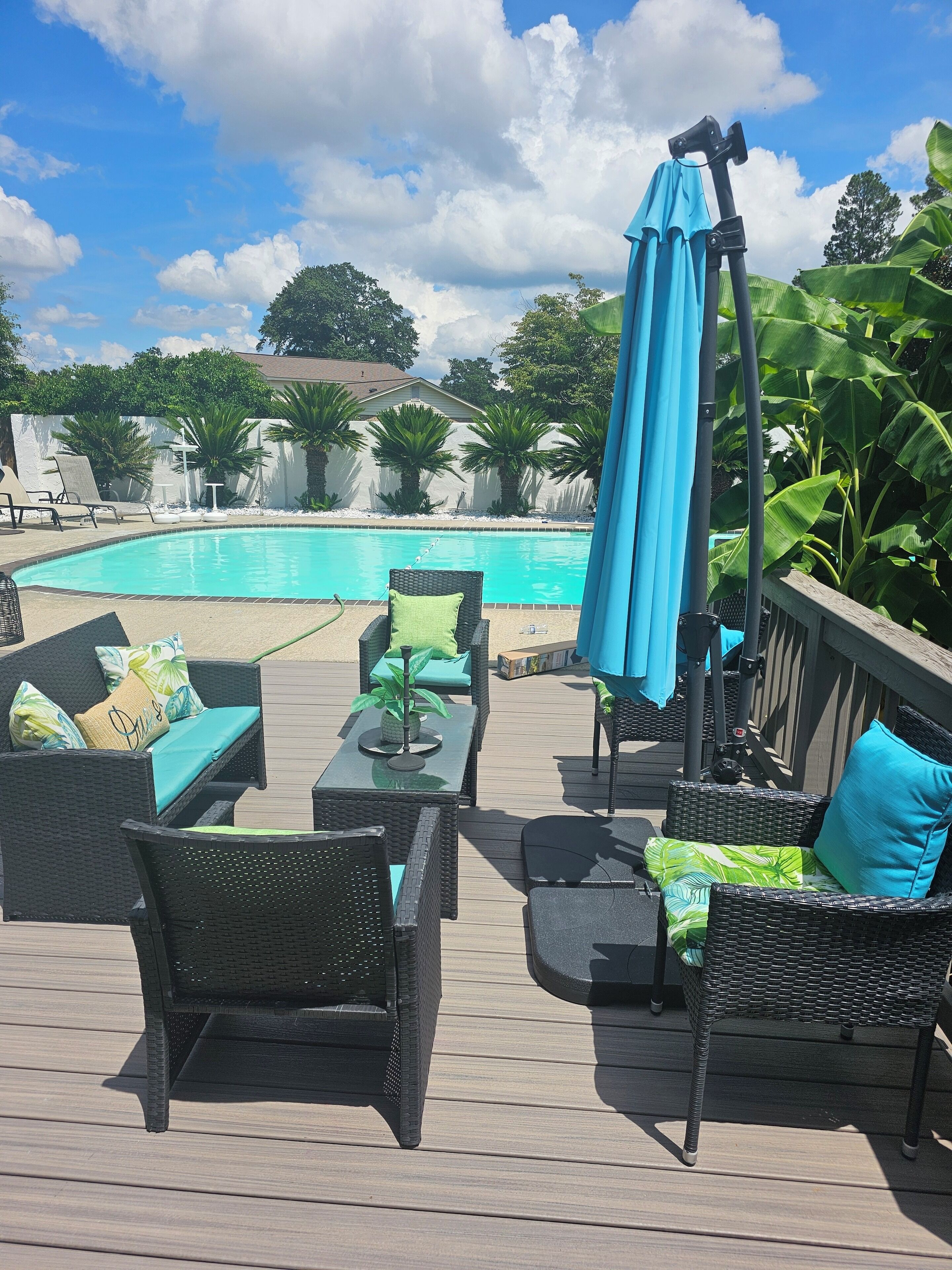 A deck with outdoor furniture, a pool, and a view of the surrounding greenery.