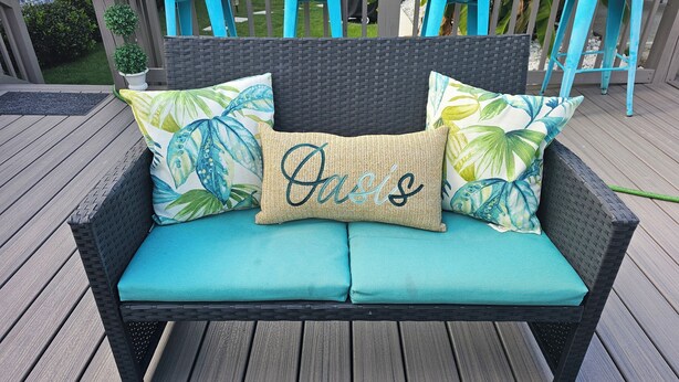 A wicker sofa with teal cushions and decorative pillows on a wooden deck. - Hidden Oasis (Martinez)