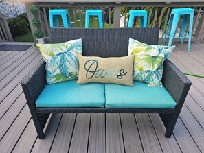 A wicker sofa with teal cushions and decorative pillows on a wooden deck. - Hidden Oasis (Martinez)