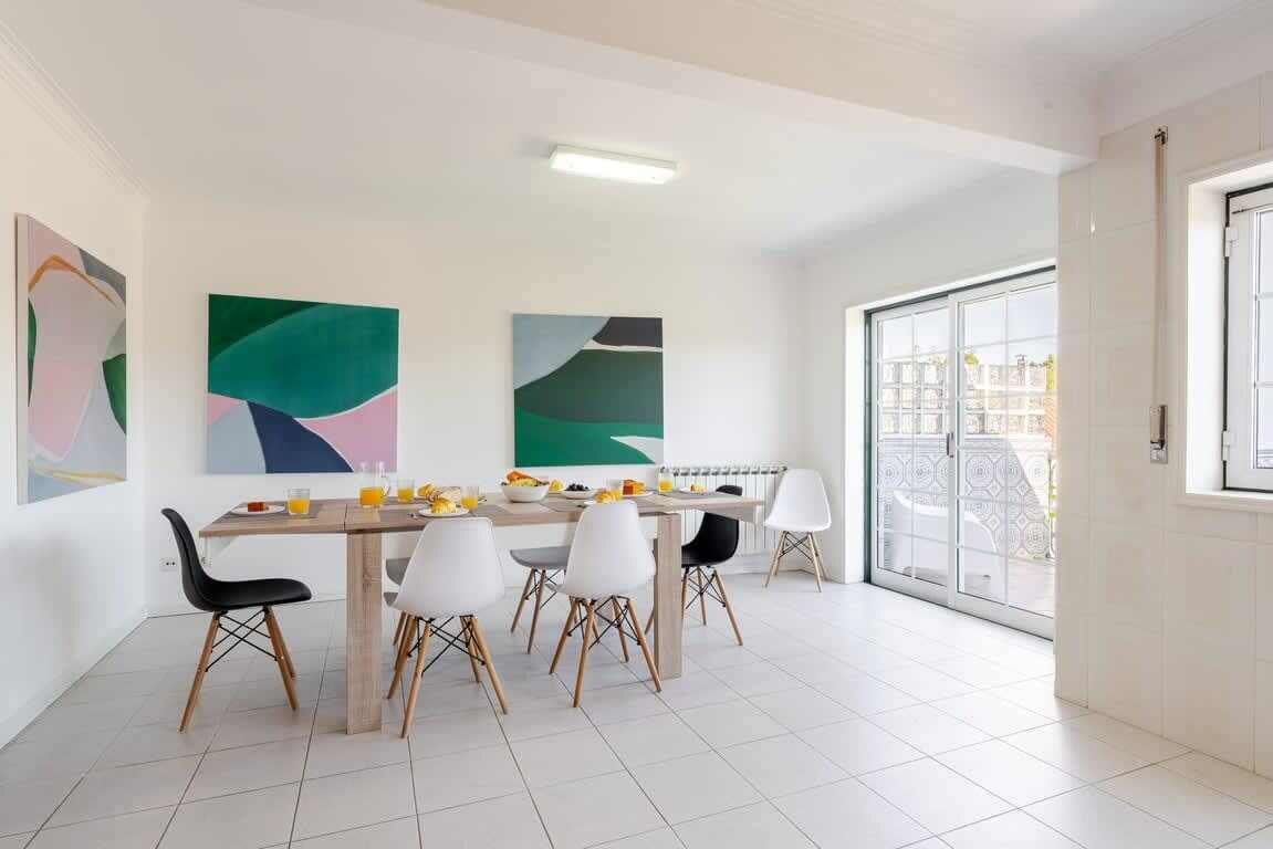 A dining area with a table, chairs, and abstract art on the walls.