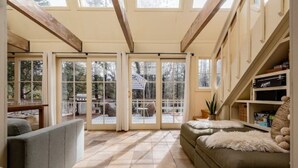 A sunlit room with a large sliding glass door leading to an outdoor patio, a sofa, and a bookshelf. - Bright, Stylish, Equipped, Pet-Friendly, Great Location, Lake access, Ski lodge! (Truckee)