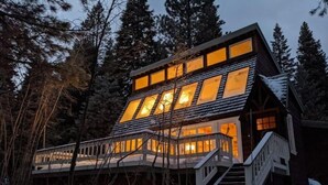 A modern cabin with a two-story structure, a covered deck, and a staircase leading to the entrance. - Bright, Stylish, Equipped, Pet-Friendly, Great Location, Lake access, Ski lodge! (Truckee)