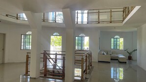 A spacious interior with high ceilings, large windows, and a central staircase.