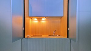 A compact kitchen with a built-in sink, overhead lighting, and a wooden backsplash. - 2 steps from the Spanish Steps (Roma)