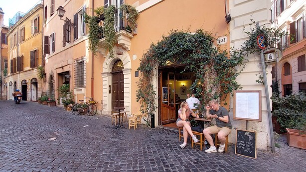 A cobblestone street with a café patio, outdoor seating, and a signboard with menu items. - 2 steps from the Spanish Steps (Roma)