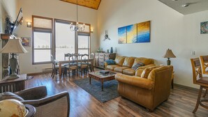 A spacious living room with a high ceiling, wooden flooring, a leather sofa, a coffee table, and a dining area with wooden chairs and a table. - Picturesque Pagosa Springs Retreat w/ Mtn Views! (Pagosa Springs)