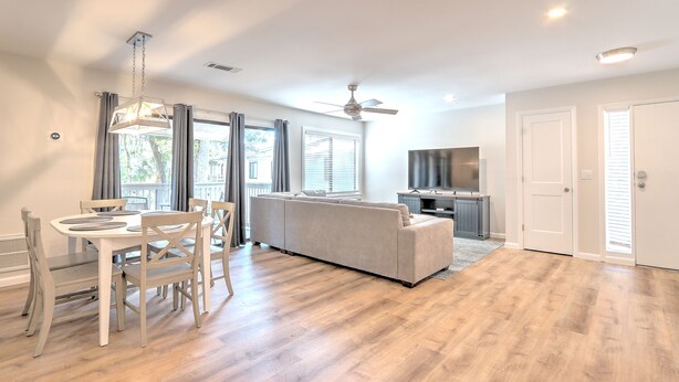 A spacious living area with a sofa, dining table, and chairs, a ceiling fan, and a TV. - Newly updated in Forest Gardens (Hilton Head Island)