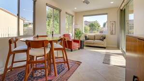 A spacious living room with a dining area, large windows, a ceiling fan, and a view of the outdoors.