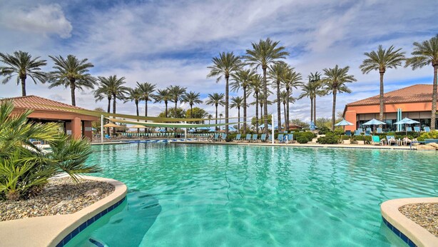 A swimming pool with clear water, surrounded by palm trees and lounge chairs.