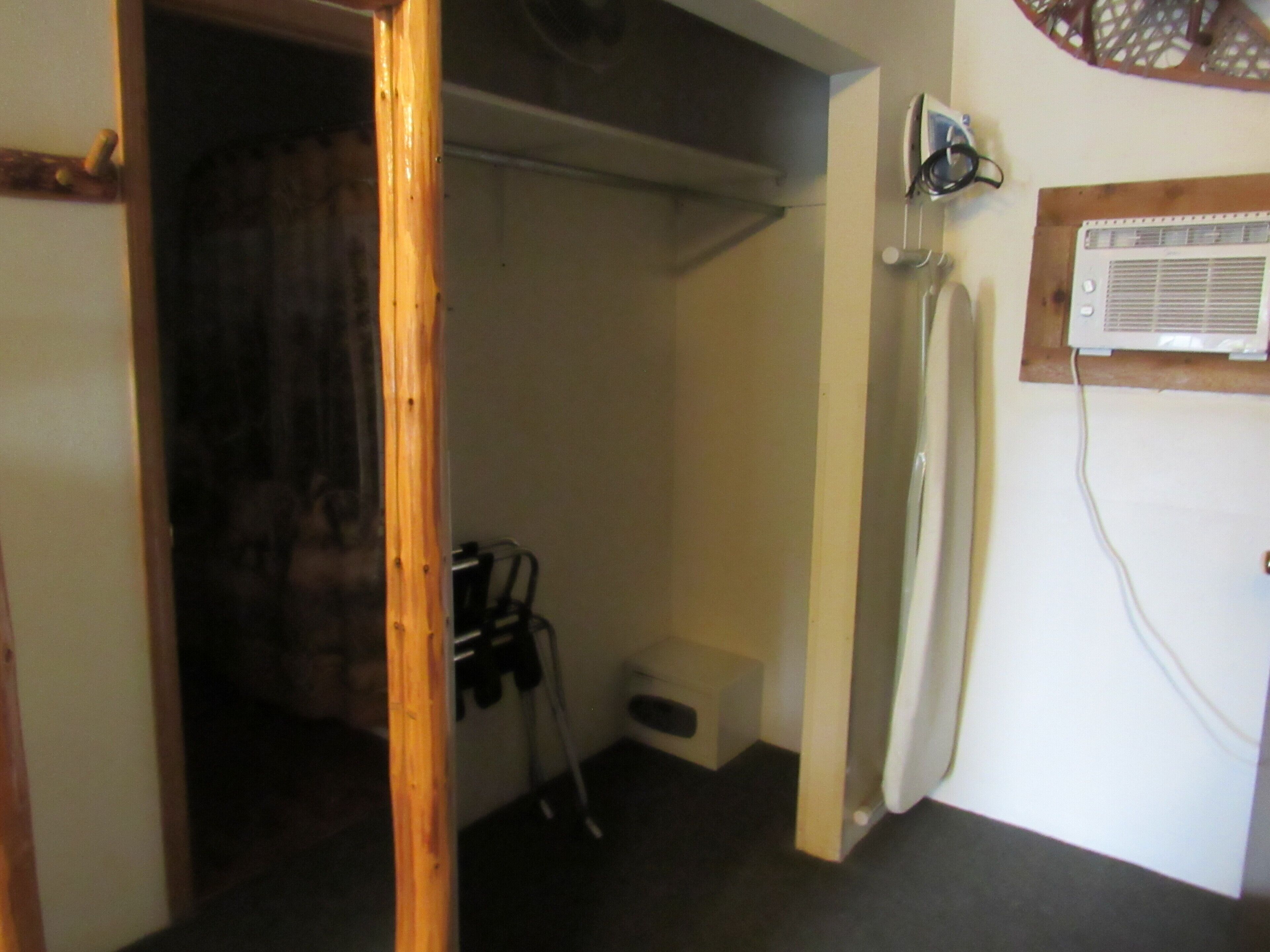 A room with a wooden door, a white radiator, a shower, and a small step leading to a bathroom.