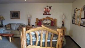 Ein Schlafzimmer mit einem hölzernen Bettgestell, einer Couch und einem Wandbild mit einem Hirsch.