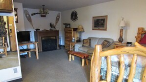 Ein gemütliches Wohnzimmer mit Kamin, Holzmöbeln und einem Fernseher.