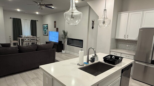 A modern kitchen with a central island, stainless steel appliances, and a dining area with a TV. - Cozy and stylish 4Bedroom 4.5bath Townhome (Lewisville)