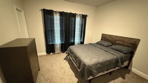 A bedroom with a bed, a dresser, and a window with curtains. - Cozy and stylish 4Bedroom 4.5bath Townhome (Lewisville)