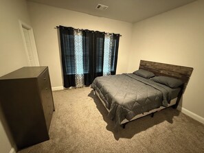 A bedroom with a bed, a dresser, and a window with curtains. - Cozy and stylish 4Bedroom 4.5bath Townhome (Lewisville)