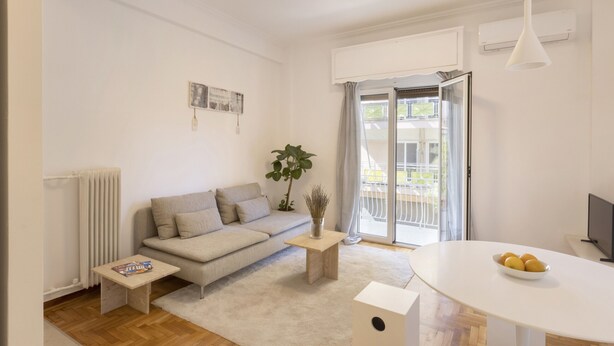 A modern living room with a sofa, coffee table, and a dining table with fruit. - Kerameikou25 small ·  Excellent value for money in (Athens)
