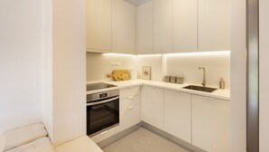 A compact kitchen with white cabinetry, a built-in oven, a sink, and a countertop with a toaster and a small decorative item. - Kerameikou25 small ·  Excellent value for money in (Athens)