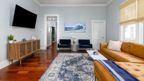 A living room with a sofa, a coffee table, a TV mounted on the wall, and a patterned rug.