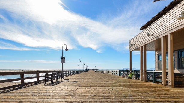 A wooden pier extending into the water with benches and a covered area on the right.