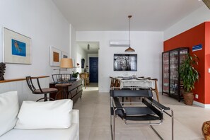Un salon moderne comprenant un canapé, une table à manger avec des chaises et un coin cuisine avec des placards.