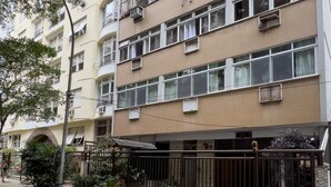 Un immeuble résidentiel à plusieurs étages, doté de balcons, de climatiseurs et d’une entrée sécurisée par un portail.