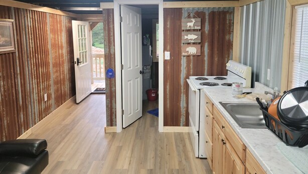 Une cuisine rustique avec des murs en bois, un poêle blanc et un évier.