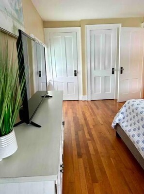 Un dormitorio con una cama, un aparador, un televisor y dos puertas.