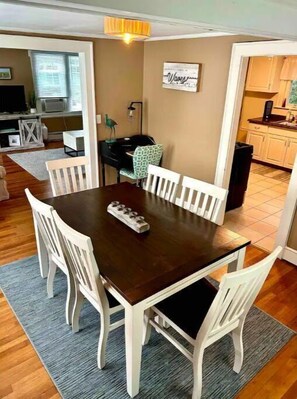 Un comedor con una mesa de madera oscura, sillas blancas y un pequeño objeto decorativo sobre la mesa.