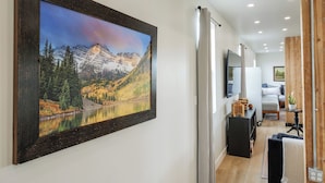 A hallway with a framed landscape painting, a wooden door, and a bed with a view of the mountains. - Newly renovated Barnhouse on 13 acres brings you a modern feel to your retreat.  (Grand Junction)
