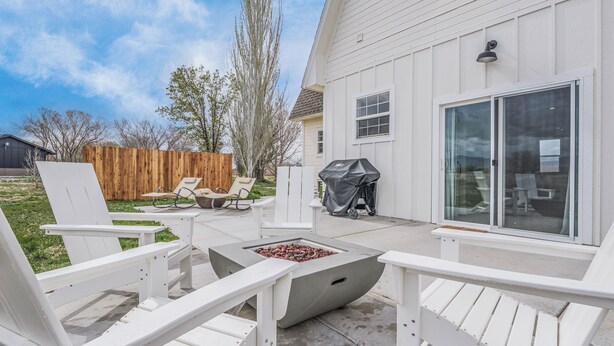 A patio area with Adirondack chairs, a fire pit, and a grill. - Newly renovated Barnhouse on 13 acres brings you a modern feel to your retreat.  (Grand Junction)