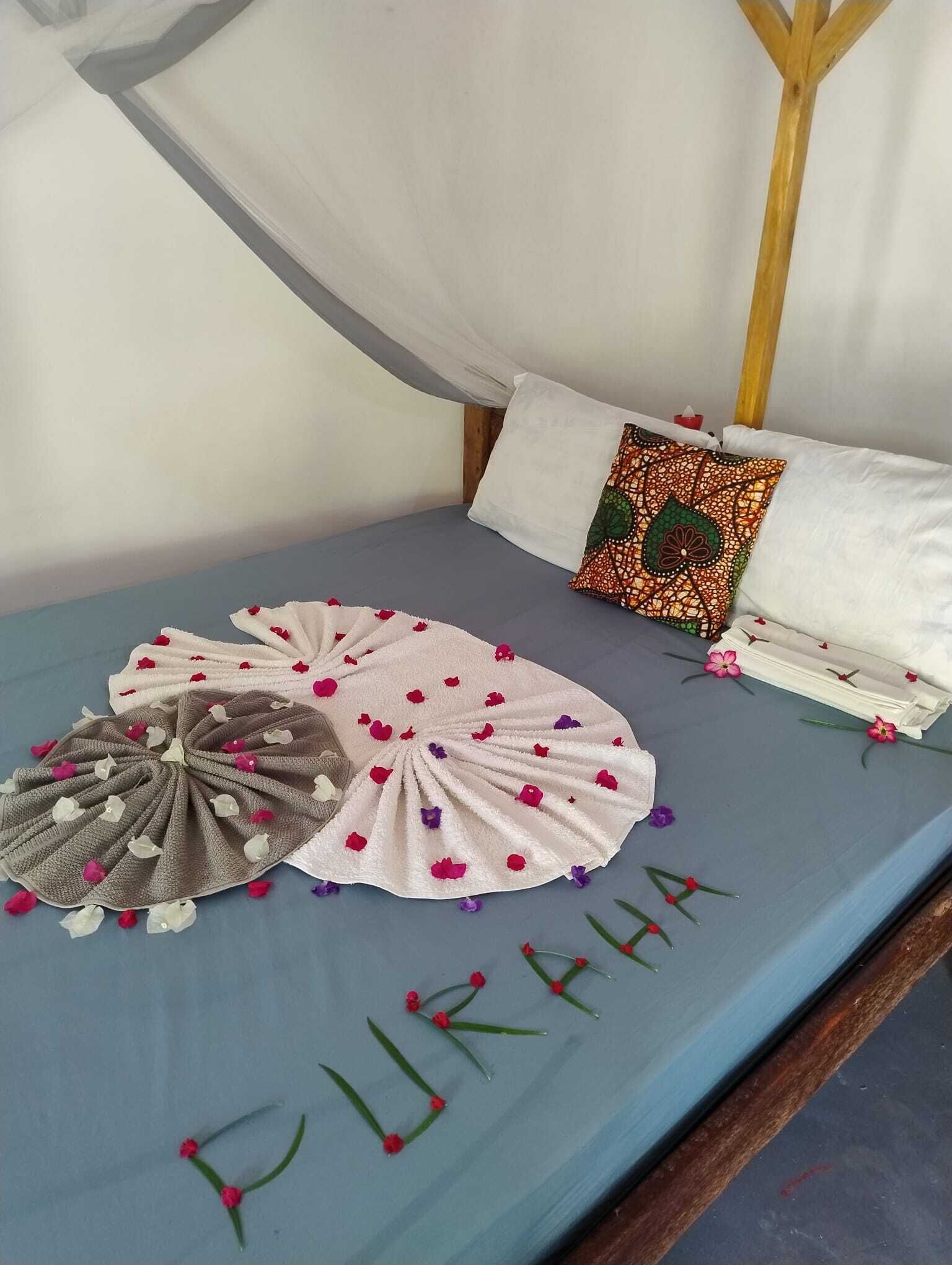 Una cama con sábana azul, una toalla decorativa y un cojín estampado.