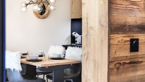 Un espace repas avec une table en bois, des chaises noires et un lustre moderne.