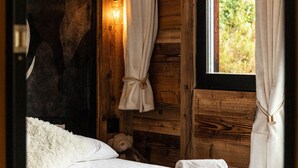 Une pièce en bois avec un lit, un mur en pierre et une fenêtre avec des rideaux.